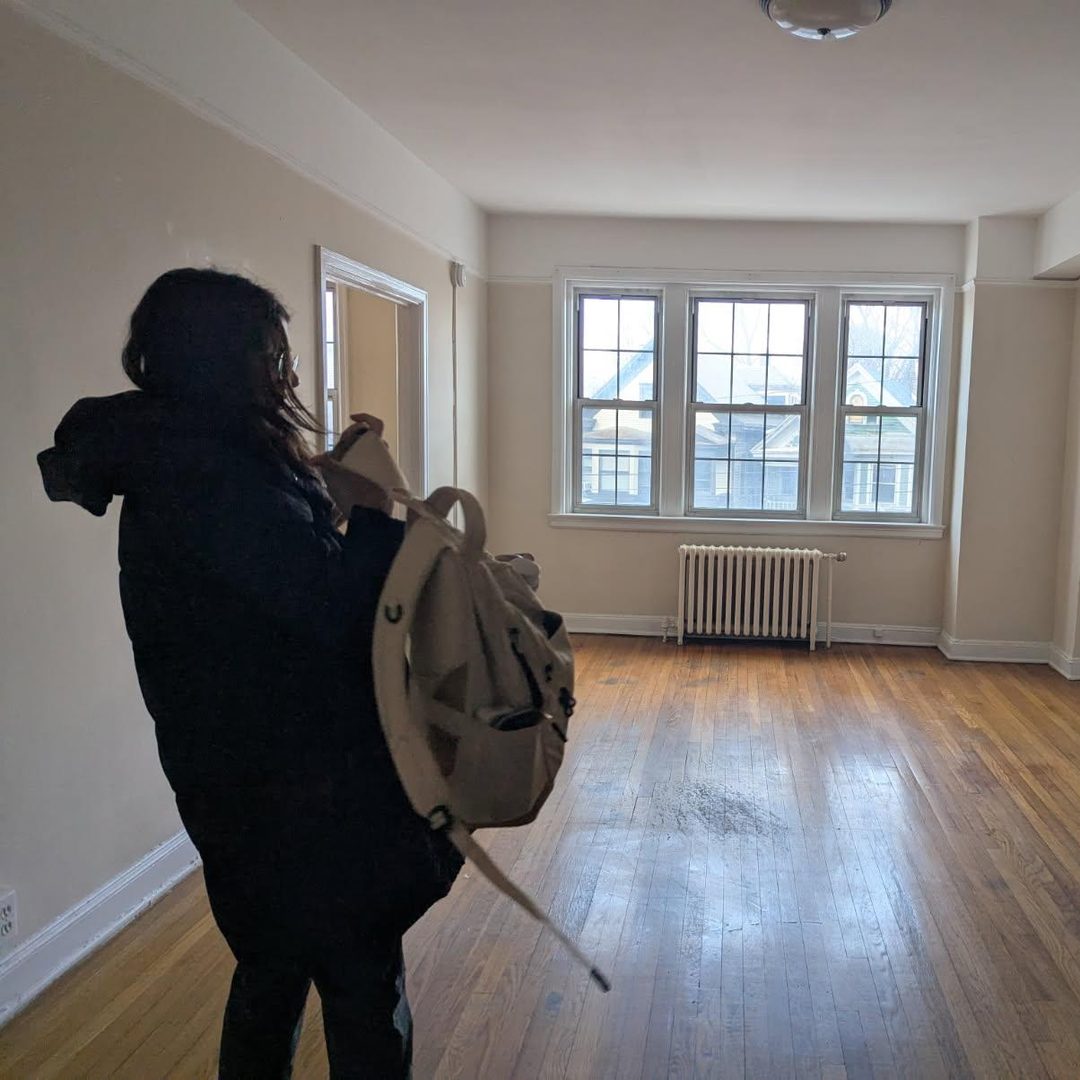 Olivia in an empty apartment on moving day, backpack on, taking one last look